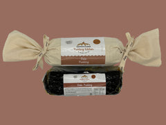 Two packages of Date log Pudding from one calico wrapped with ribbon and the other in a vacuum sealed bag Adamstown Kitchen on a white background