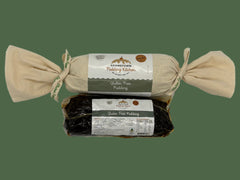 Two packages of gluten-free puddings one wrapped in calico with ribbon and one in a vacuum sealed bag from Adamstown Pudding Kitchen on a white background.